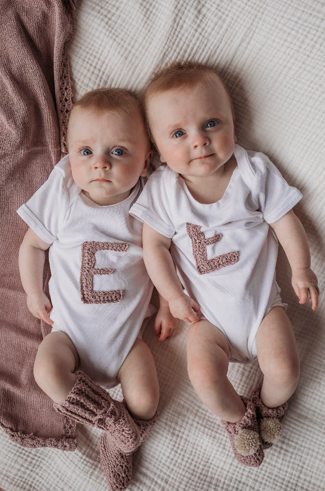 Image shows twins wearing matching personalised organic cotton vests