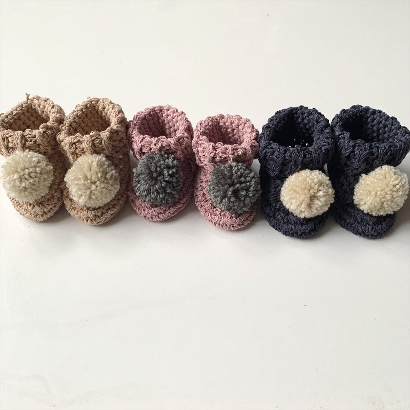 image shows three pairs of organic cotton baby booties in beige, pink and navy