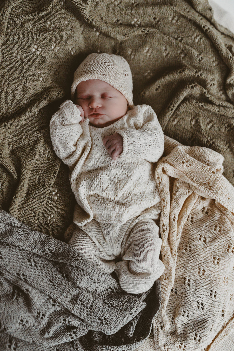 image shows a baby wearing a gooseberry fool outfit lay on silk baby swaddles